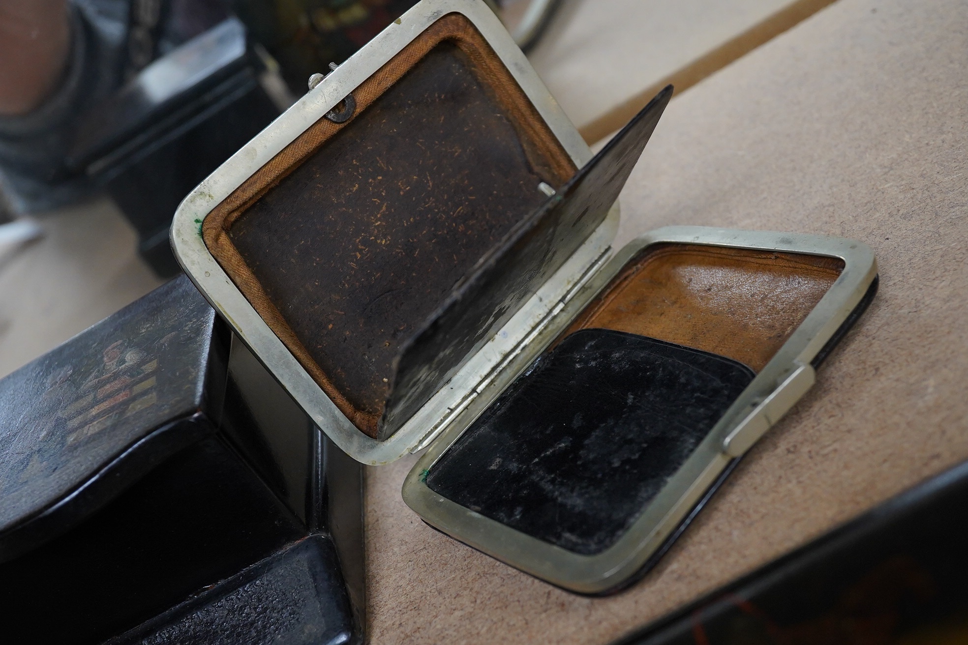 Three Russian lacquer cigarette cases, late 19th/early 20th century, one decorated with a troika scene and a match strike, 11cm wide. Condition - good